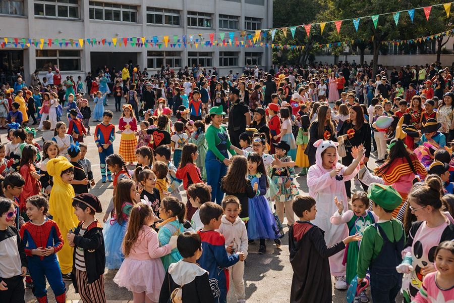 Carnestoltes al pati – Escola Closa Pati d’escola ple d’alumnat de totes les edats disfressat i jugant en grups durant Carnestoltes, amb docents també disfressats.